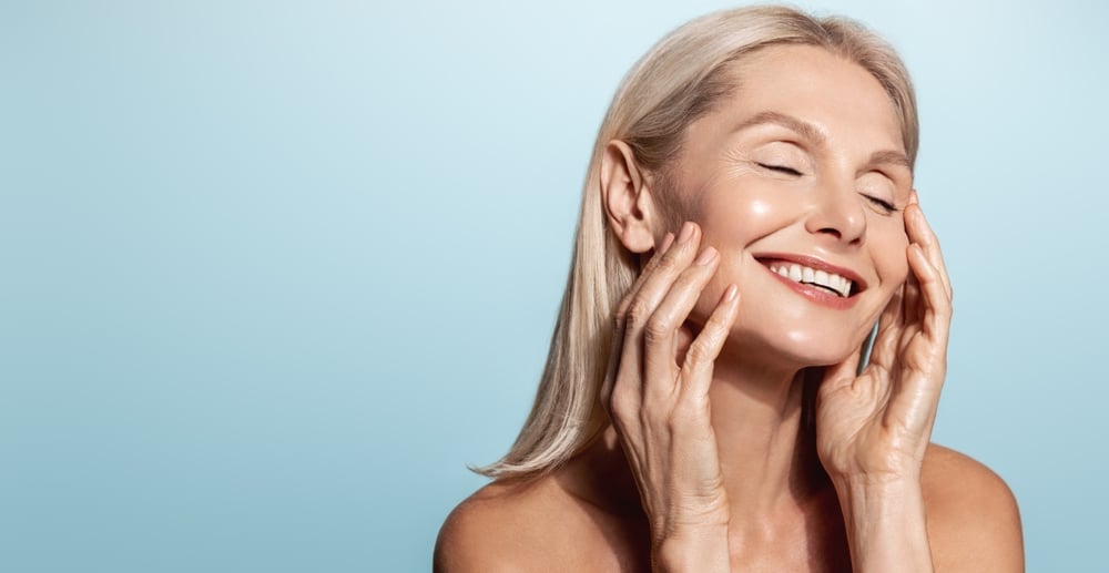 Woman smiles in delight, eyes closed, after her skin rejuvenation with UltraGLO