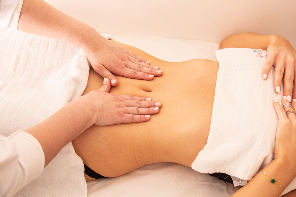 Woman receives a lymphatic massage on her abdomen from a professional.