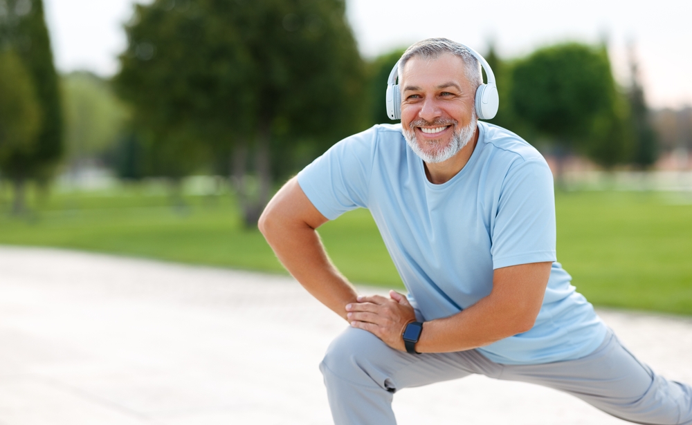 Older man with headphones exercises in the park with renewed energy from TRT.